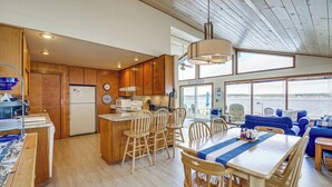 A spacious kitchen with wooden cabinets, a central island, and a dining area with wooden chairs and a table.