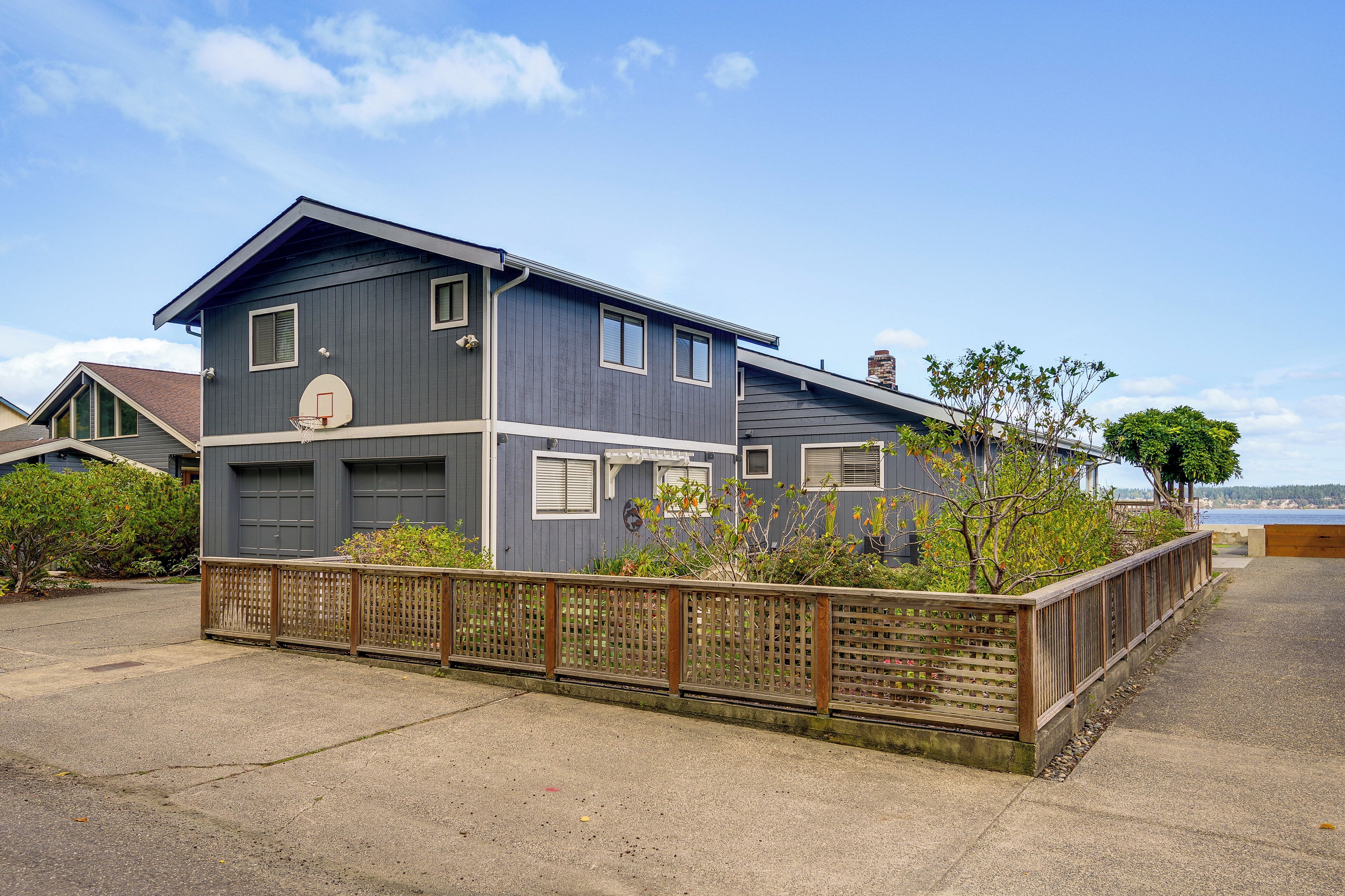 A two-story residential house with a garage, a basketball hoop, and a view of the water.