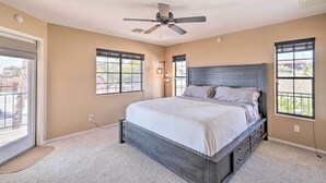 Ein Schlafzimmer mit einem Bett, einem Deckenventilator und großen Fenstern.