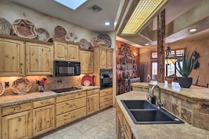 A kitchen with wooden cabinets, a black microwave, an oven, and a sink. - Patio, Grill & Yard: Pet-friendly Lake Havasu Gem (Lake Havasu City)