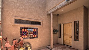 A building with a textured exterior, a wooden door, a window with a decorative tile, and a cactus plant. - Patio, Grill & Yard: Pet-friendly Lake Havasu Gem (Lake Havasu City)