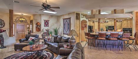 A spacious living room with leather sofas, a coffee table, and a dining area with bar stools.