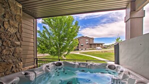 A hot tub with a stone wall and a view of a building and tree.