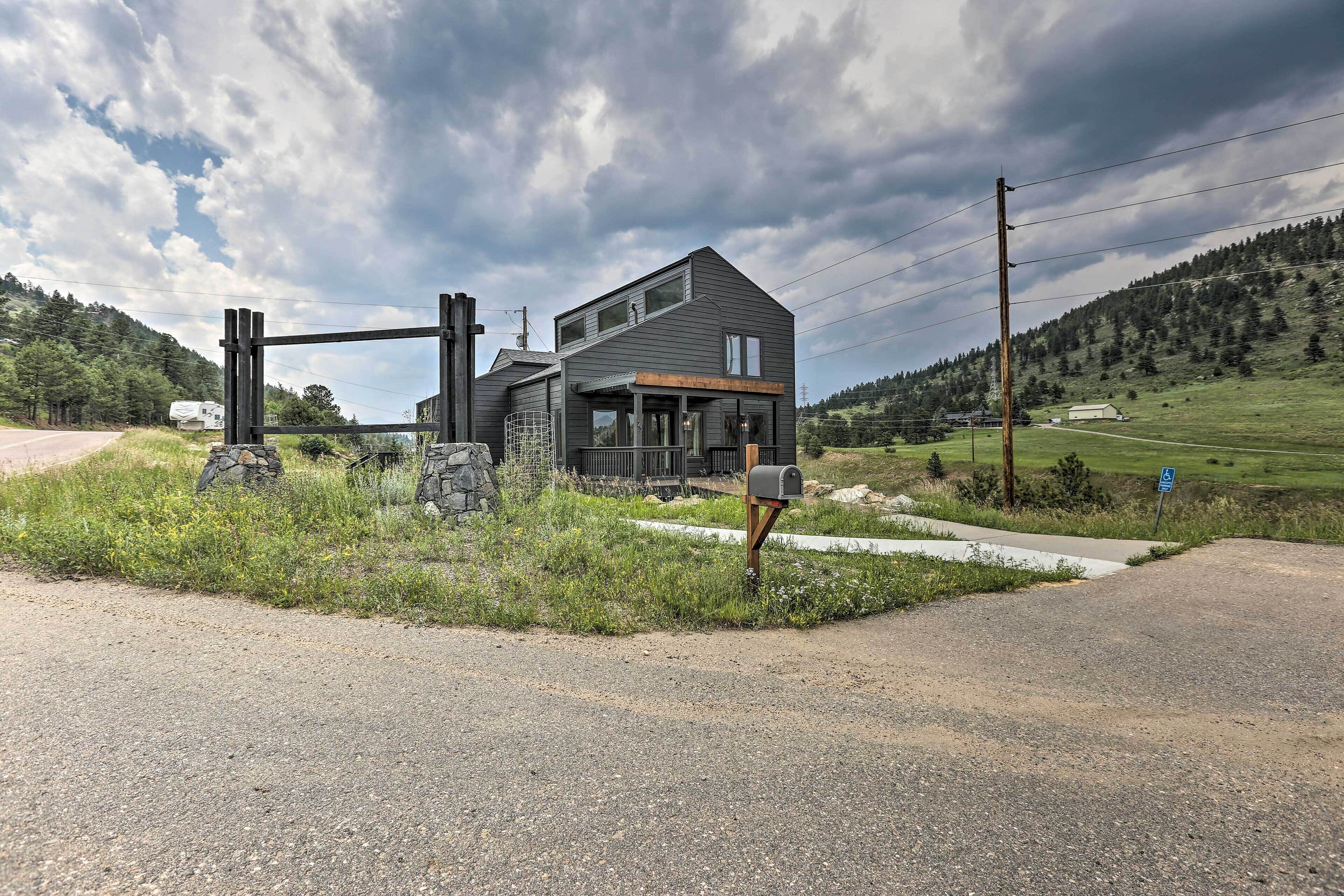 A modern two-story house with a stone archway entrance, a mailbox, and a wheelchair-accessible sign.