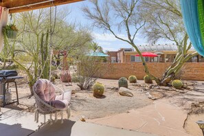 A patio with a hanging chair, cacti, and a brick wall. - Private Desert Garden: Cozy Tucson Casita (Tucson)