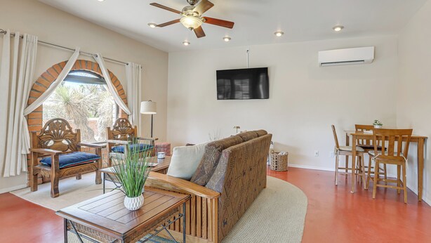 Un salon comprenant un canapé, des chaises en bois, une table à manger et un ventilateur de plafond.