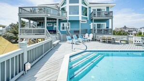 Une grande maison dotée d’une piscine, de nombreux balcons et de mobilier d’extérieur.