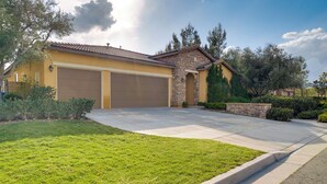 A residential house with a garage, a stone facade, and a well-maintained lawn. - Single-story San Bernardino Home w/ Valley Views! (San Bernardino)