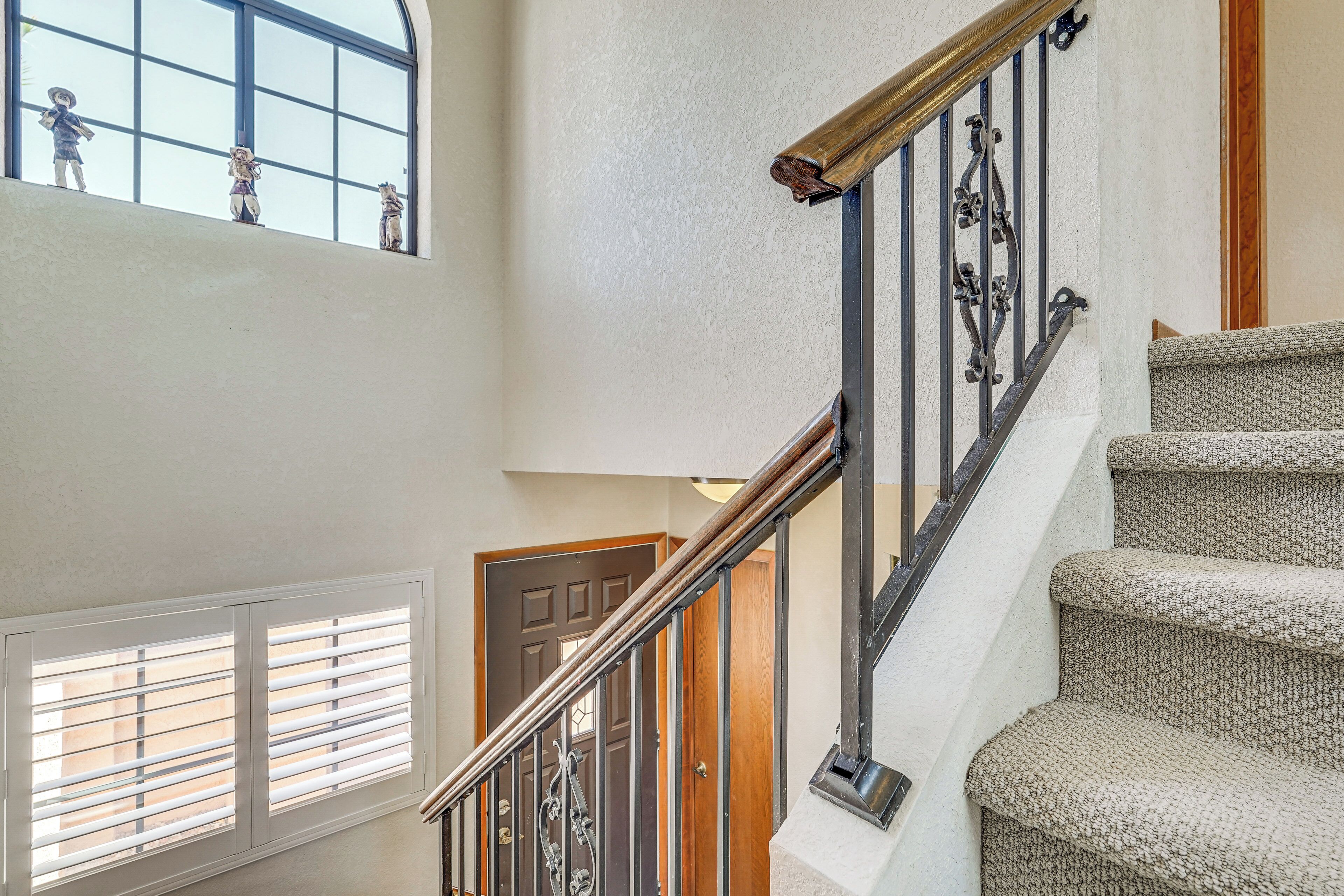A staircase with a wooden handrail and metal balusters, leading to a landing with a door.