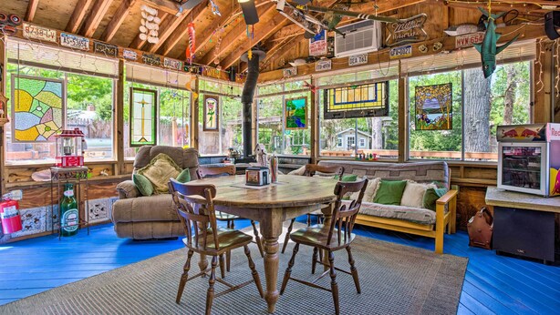 Interior acogedor de una cabaña con una mesa de comedor de madera, sillas, un sofá y un televisor.