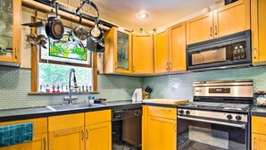 Una cocina con armarios de madera, lavavajillas, microondas, estufa y salpicadero de azulejos.