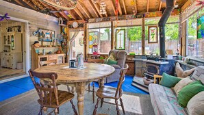 Interior rústico de una cabaña con una mesa de comedor de madera, sillas, un sofá y una chimenea.