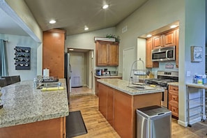 A modern kitchen with granite countertops, wooden cabinets, stainless steel appliances, and a central island. - Flagstaff Home w/ Mountain View! (Flagstaff)