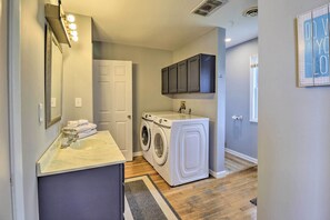 A compact laundry room with a washing machine, a sink, and a mirror.