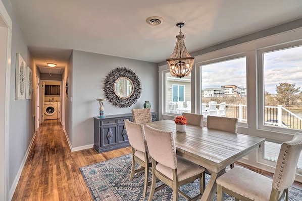 A dining area with a table and chairs, a chandelier, a decorative mirror, and a view of the outside.