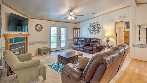 A living room with a fireplace, leather sofas, a television, and a ceiling fan. - Cedar Creek Lake Access: Retreat w/ Deck (Kemp)