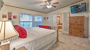 A bedroom with a bed, a ceiling fan, a television, and a wooden cabinet. - Cedar Creek Lake Access: Retreat w/ Deck (Kemp)