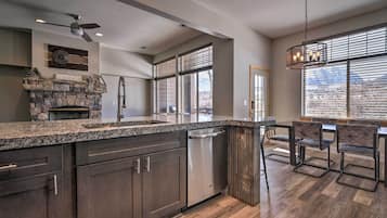 A kitchen with dark wood cabinets, a stone fireplace, and a dining area with four chairs.