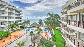 Un resort con varios balcones, una piscina y vista al océano.