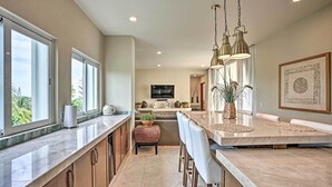 Una cocina moderna con una isla grande, taburetes de bar e iluminación colgante.