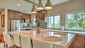 Una cocina moderna con una isla grande, armarios de madera e iluminación colgante.