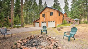 A cabin with a fire pit and two Adirondack chairs in front. - Cabin w/ Hot Tub, By Crater Lake Nat'l Park! (Klamath Falls)