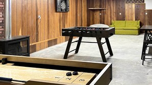 A room with a foosball table, a dartboard, and a green couch. - Cabin w/ Hot Tub, By Crater Lake Nat'l Park! (Klamath Falls)