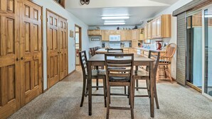A spacious kitchen with wooden cabinets, a central island, and a dining area with chairs. - Cabin w/ Hot Tub, By Crater Lake Nat'l Park! (Klamath Falls)
