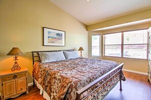 A bedroom with a bed, two bedside lamps, a nightstand, a framed picture on the wall, and a window with blinds. - Tucson Home W/pool & Santa Catalina Mtn Views (Tucson)