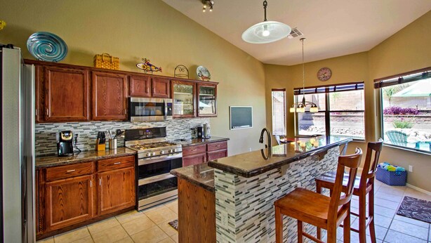 A kitchen with wooden cabinets, a central island, and a large window. - Tucson Home W/pool & Santa Catalina Mtn Views (Tucson)