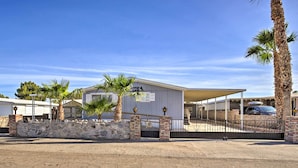 A hotel with a stone wall entrance, palm trees, and a covered parking area. - Cozy Yuma Retreat w/ Furnished Patio & Grill! (Yuma)