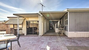 A covered patio area with a table and chairs, a brick wall, and a door leading to an interior space. - Cozy Yuma Retreat w/ Furnished Patio & Grill! (Yuma)