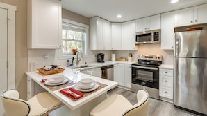 Een moderne keuken met witte kasten, roestvrijstalen apparatuur en een ontbijtbalk.