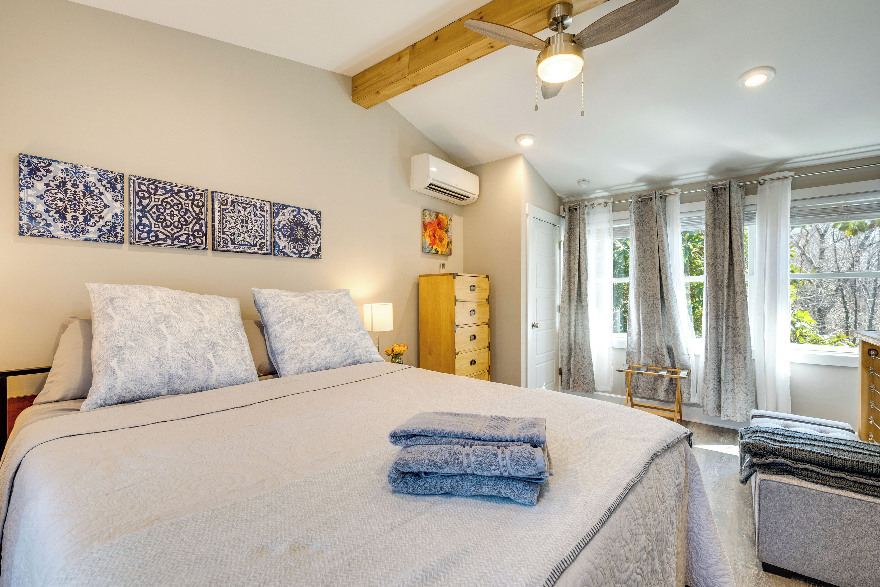 A bedroom with a large bed, a ceiling fan, and a window with curtains.