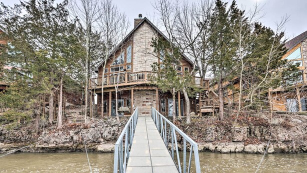 Un bâtiment en pierre doté d’une terrasse en bois et d’un pont qui enjambe une rivière et y mène.