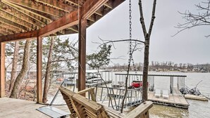 Une terrasse en bois avec une balançoire, donnant sur un quai et sur l’eau.