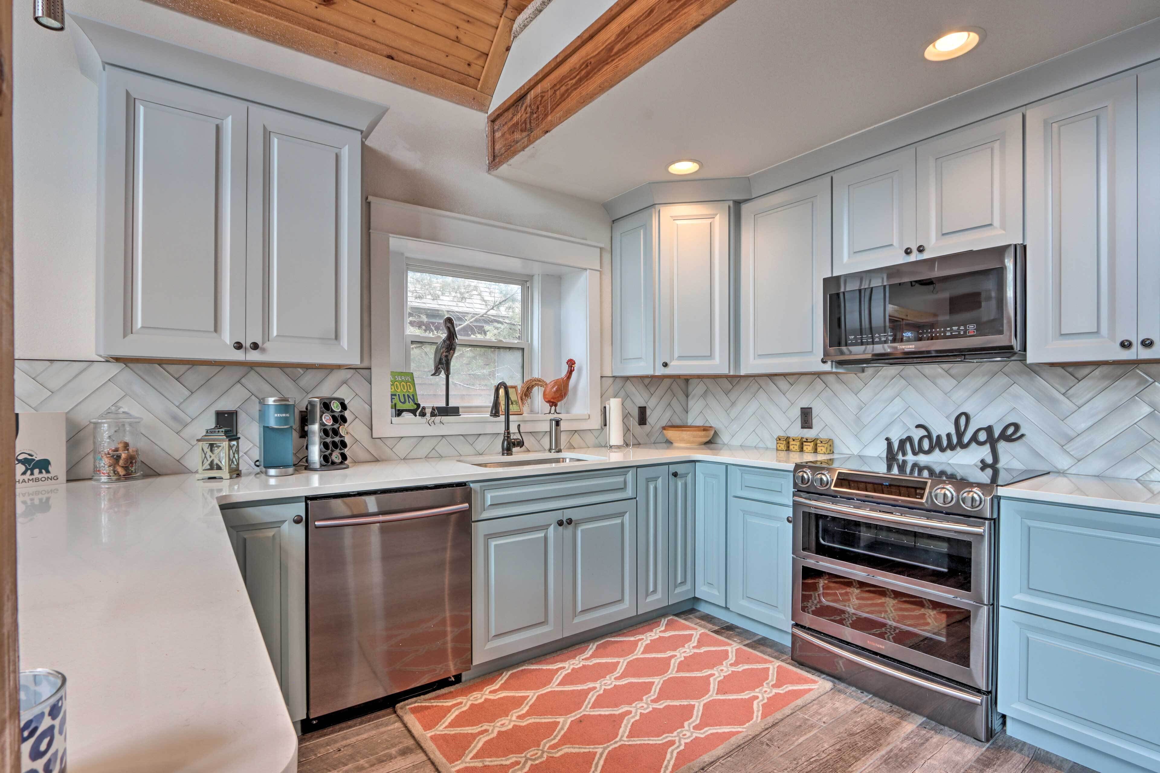 A kitchen with white cabinets, a stainless steel dishwasher, a double oven, and a herringbone tile backsplash.