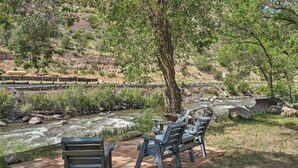 Un espace aménagé au bord de la rivière, avec des chaises et un banc, d’où l’on peut admirer le cours de la rivière et les voies ferrées.