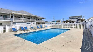 A swimming pool with blue water, surrounded by a white fence, and adjacent to a building with balconies. - Atlantic Beach Studio w/ Community Pool! (Atlantic Beach)
