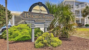 A sign for Pelican's Roost with a view of a two-story building and a clear sky. - Atlantic Beach Studio w/ Community Pool! (Atlantic Beach)