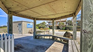 A wooden deck with a covered area, a small building with a sign, and a view of residential buildings in the background. - Atlantic Beach Studio w/ Community Pool! (Atlantic Beach)