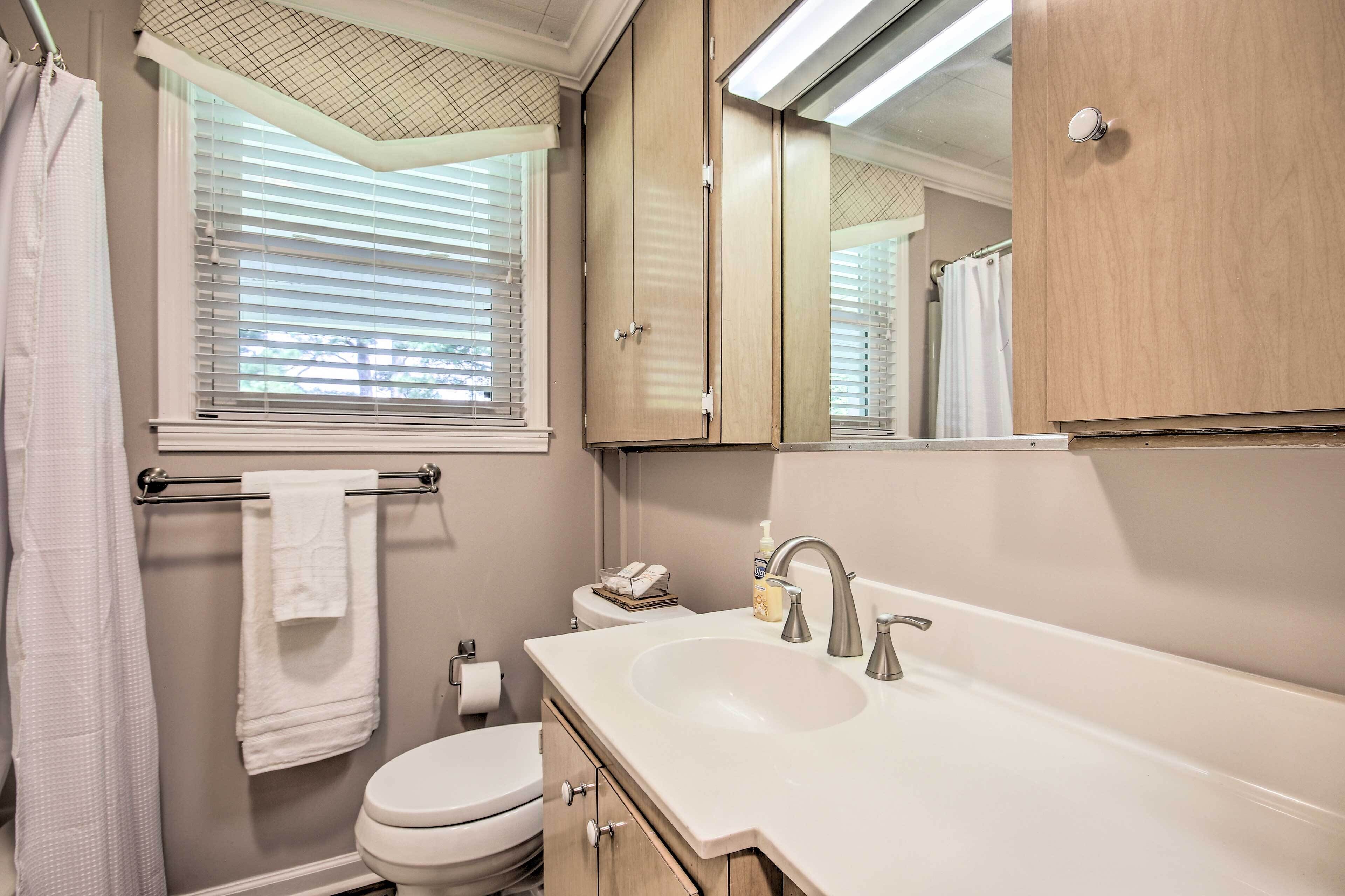A bathroom with a toilet, sink, and mirror.