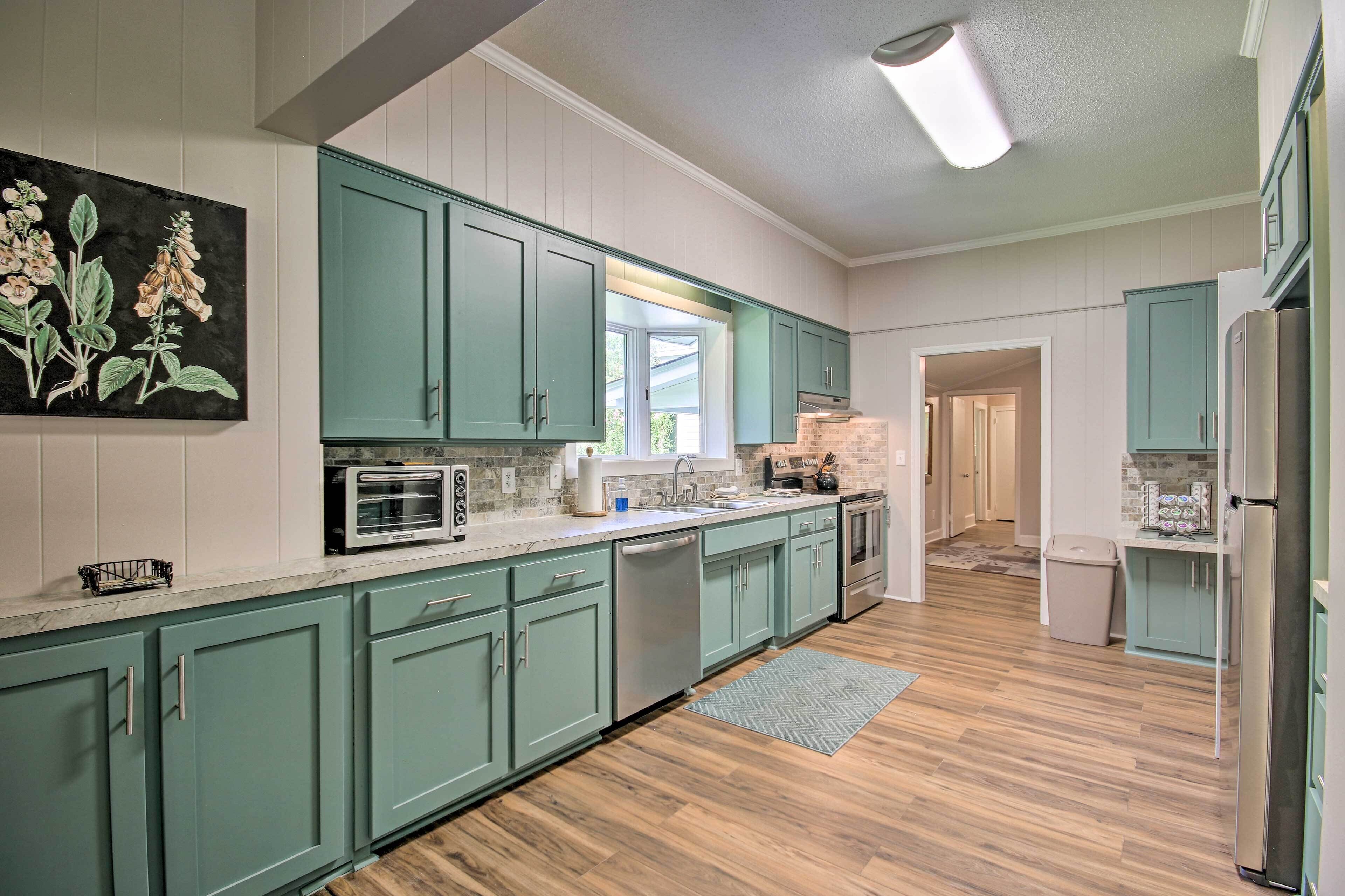A kitchen with teal cabinets, a microwave, a dishwasher, and a refrigerator.