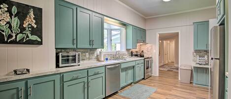 A kitchen with teal cabinets, a microwave, a dishwasher, and a refrigerator.