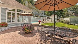 Une terrasse avec une table ronde en métal et des chaises, entourée de plantes en pot et de parasols.