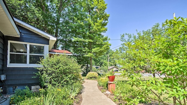 A residential property with a concrete pathway leading to a dark blue house with white trim. - Stylish Dog-friendly Bungalow: Steps to Elk Lake (Elk Rapids)