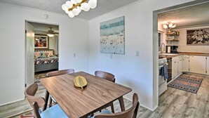 A dining area with a wooden table and chairs, a ceiling light fixture, and a painting on the wall. - Stylish Dog-friendly Bungalow: Steps to Elk Lake (Elk Rapids)