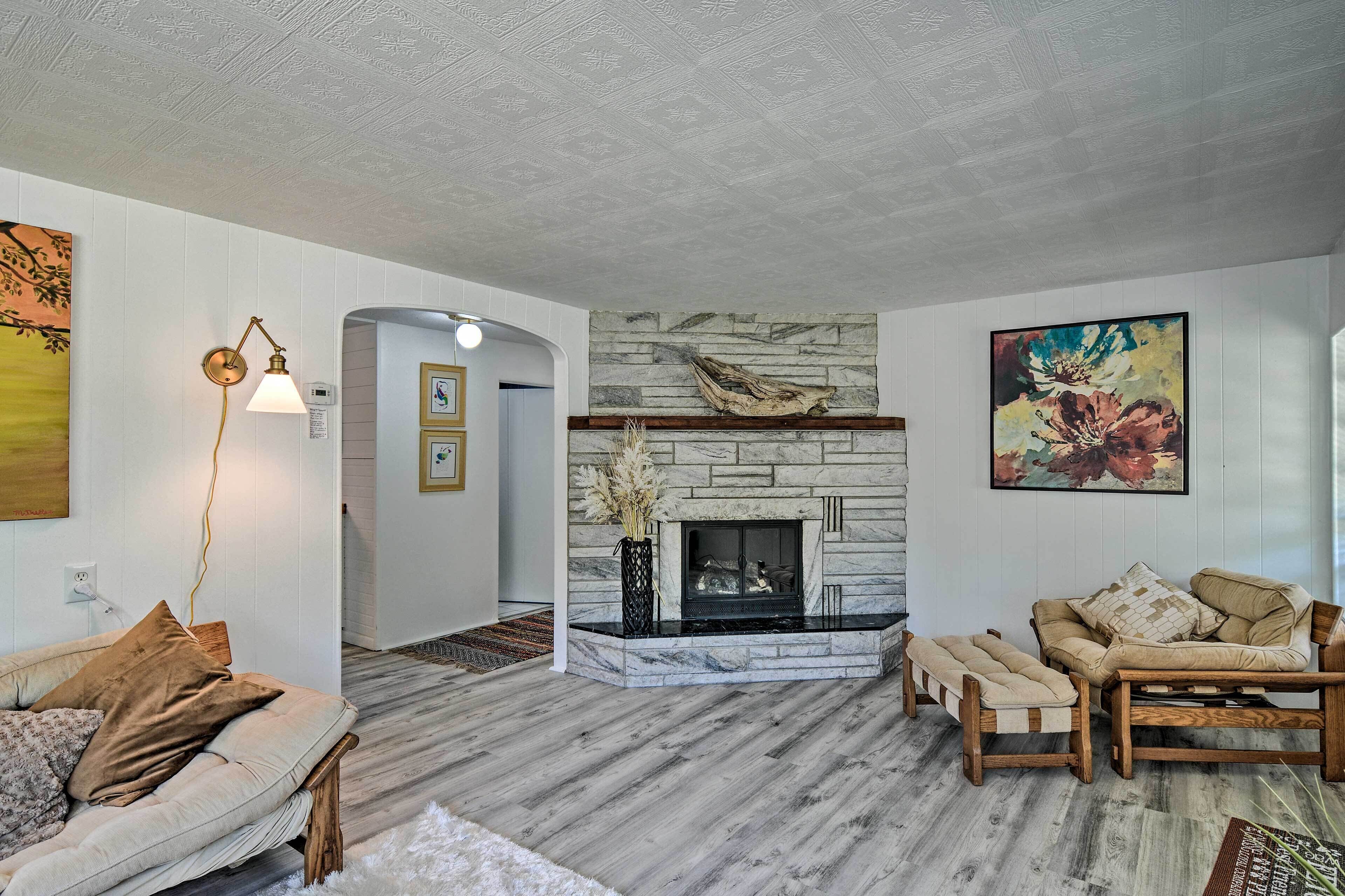 A living room with a stone fireplace, a sofa, a bench, and a painting on the wall.