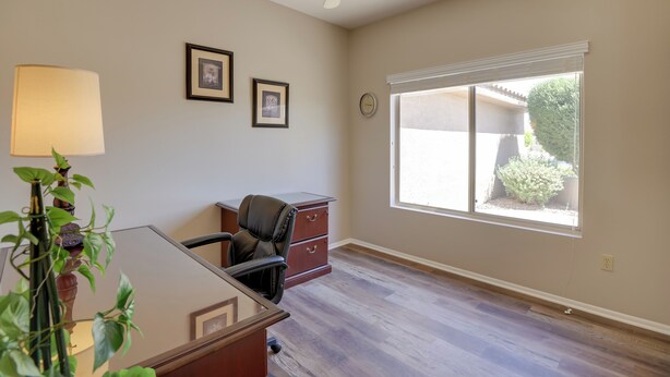 A room with a desk, chair, and a window with blinds. - Inviting Surprise Home With Covered Patio! (Surprise)