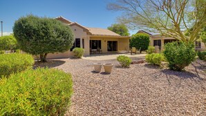 A house with a patio, surrounded by well-maintained landscaping and a gravel driveway. - Inviting Surprise Home With Covered Patio! (Surprise)